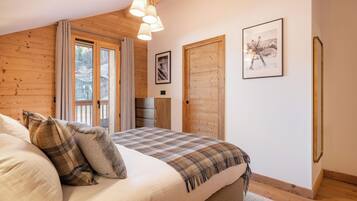 Une chambre à coucher avec un grand lit, des murs en bois, une fenêtre et une porte.