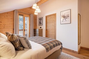 Une chambre à coucher avec un grand lit, des murs en bois, une fenêtre et une porte.