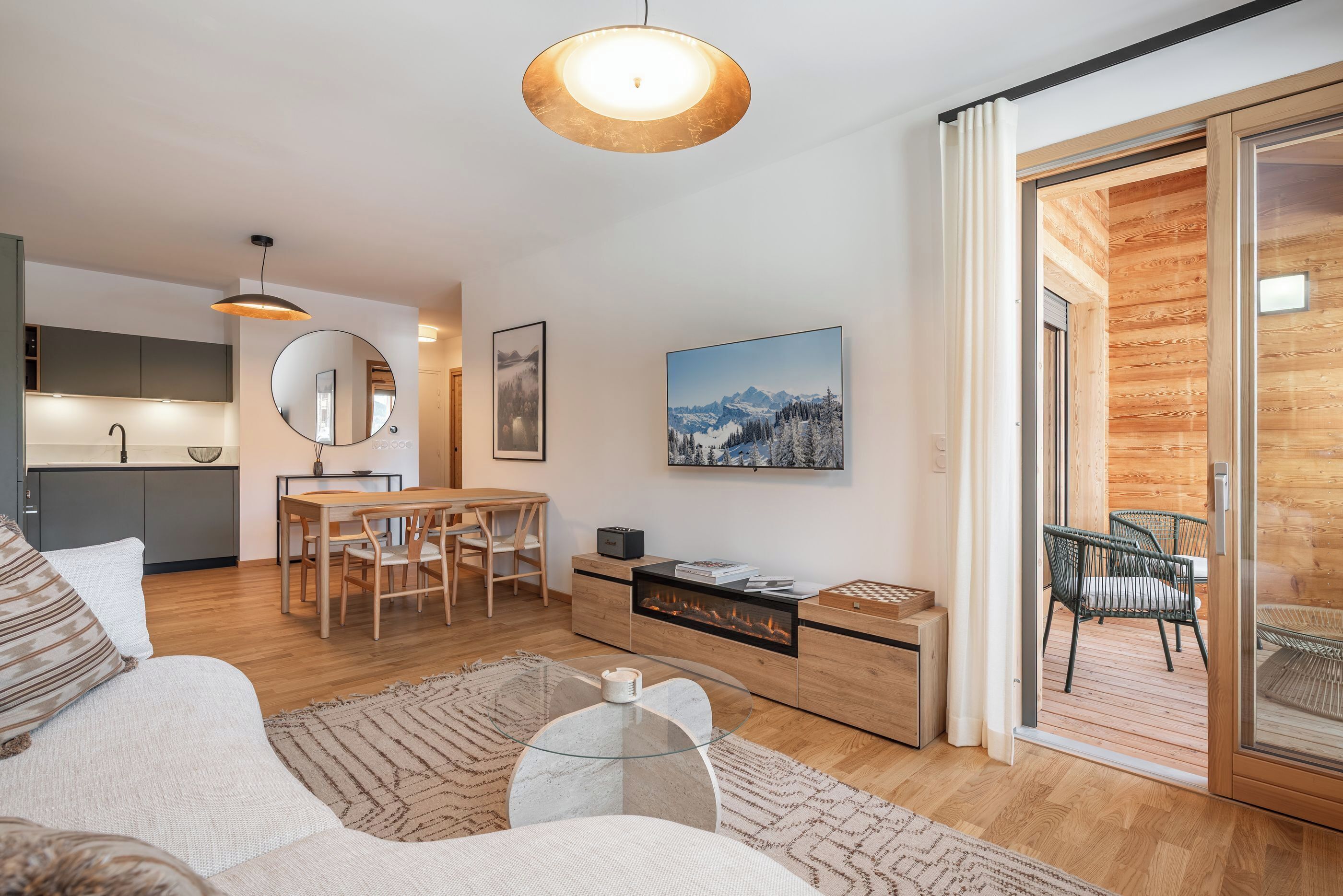 Una sala de estar moderna con sofá, mesa de centro y comedor. Cuenta con chimenea, un ventanal grande y una puerta corrediza de vidrio que da a una terraza exterior.