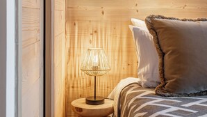 A wooden-paneled room with a bed, a nightstand, and a lamp. - Kandahar – Warm Alpine Retreat in Les Gets (Les Gets)