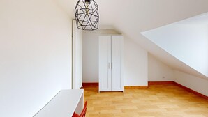 Une pièce avec une armoire blanche, une table blanche et un luminaire au design géométrique.