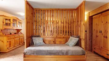 A wooden room with a bed, wooden cabinets, and a slatted wall.