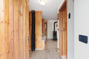 A wooden hallway leading to a bedroom with a bed, a radiator, and a black heater. - Petit Logement Cerise "L'écrin d'Ari" – Comfort and Perfect Location (La Cerise)