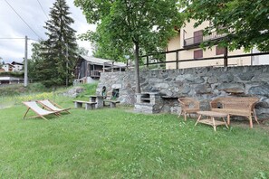 Un mur de pierre, des meubles en osier et une zone herbeuse.