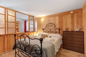 Una habitación con paneles de madera, una cama, un tocador y un espejo grande.