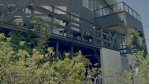 Um edifício moderno com telhado plano, janelas amplas e uma varanda.