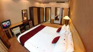 Une chambre d’hôtel équipée d’un lit, d’un bureau, d’une télévision, d’un miroir et d’une lampe.