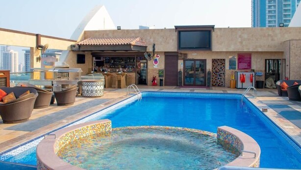 Un espace piscine aménagé sur le toit, avec un jacuzzi, des chaises longues et un bar.