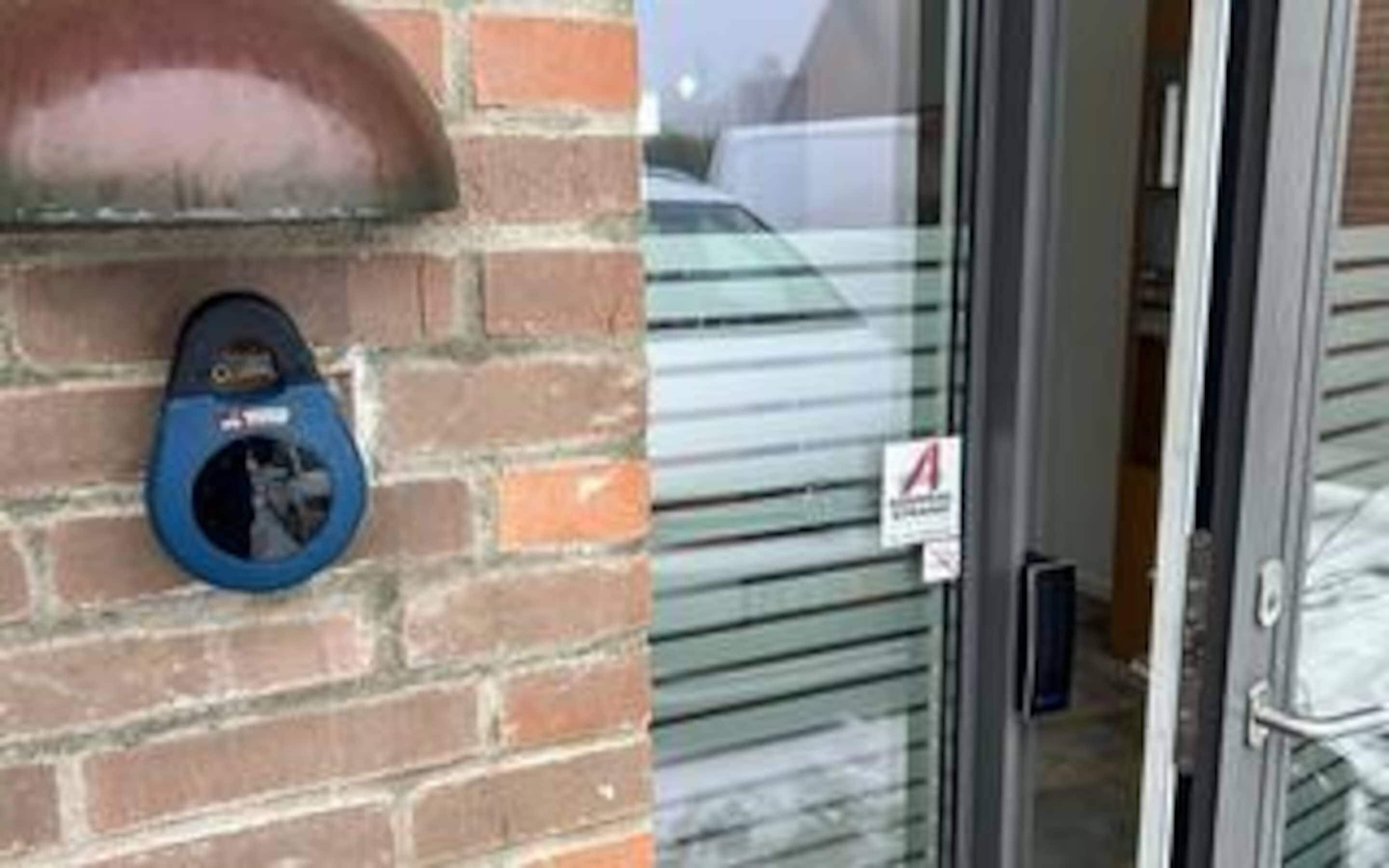A brick wall with a blue object, a glass door with a sign, and a metal handle.