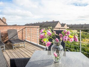 Eine Dachterrasse mit Tisch, Stühlen und einem Blumenstrauß.