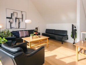 A modern living room with a black sofa, a wooden coffee table, and a black leather chair. - 4 Star Holiday Home in Romo (Rømø)