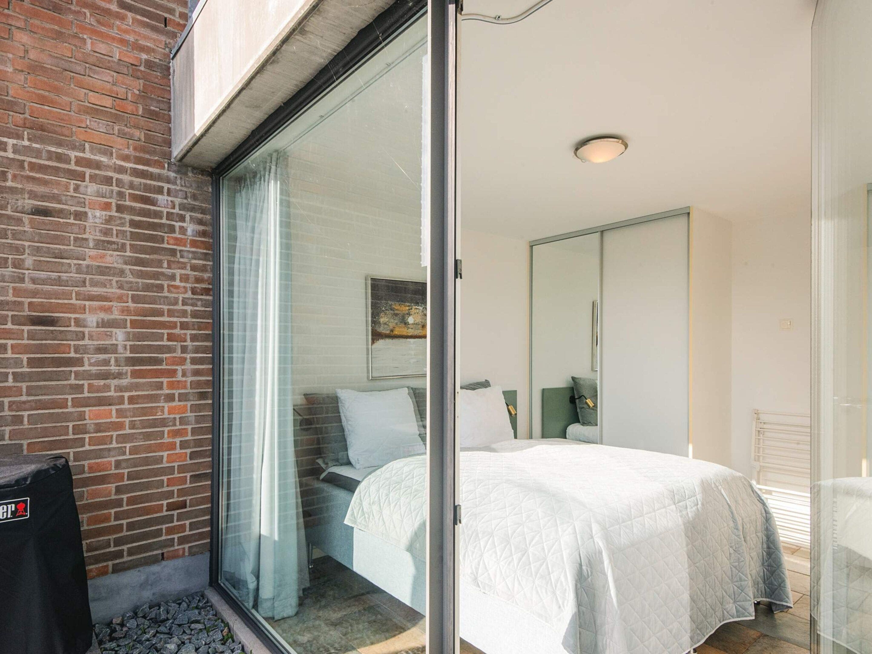 Ein Schlafzimmer mit Bett, Fenster und einer Ziegelwand.