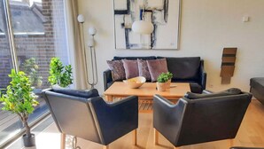 Ein modernes Wohnzimmer mit einer Couch, Sesseln, einem Couchtisch und einem Gemälde an der Wand.