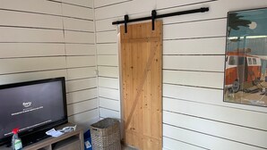 Ein Zimmer mit Fernseher, der einen Ladescreen anzeigt, einer Schiebetür, einem Korbwäscher und einem Wandbild.