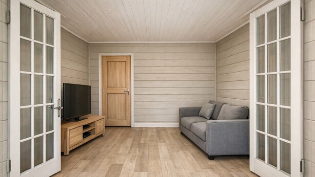 Ein Zimmer mit einem grauen Sofa, einer Holztür und einem Fernseher auf einem Holzschrank.