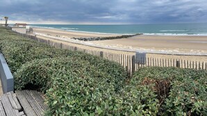 Ein Strand mit Holzzaun, Felsenmole und Blick aufs Meer.