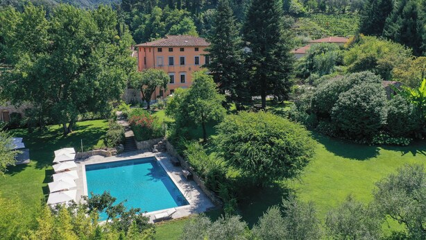 A villa with a swimming pool surrounded by lush greenery and hills in the background. - Luxury hotel apartments in tuscan borgo (Nocchi)