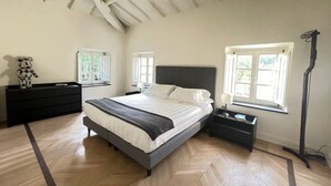 A bedroom with a large bed, two bedside tables, a dresser, and a floor lamp. - Luxury hotel apartments in tuscan borgo (Nocchi)