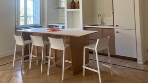 A modern kitchen with a wooden island, white chairs, and built-in cabinets. - Luxury hotel apartments in tuscan borgo (Nocchi)
