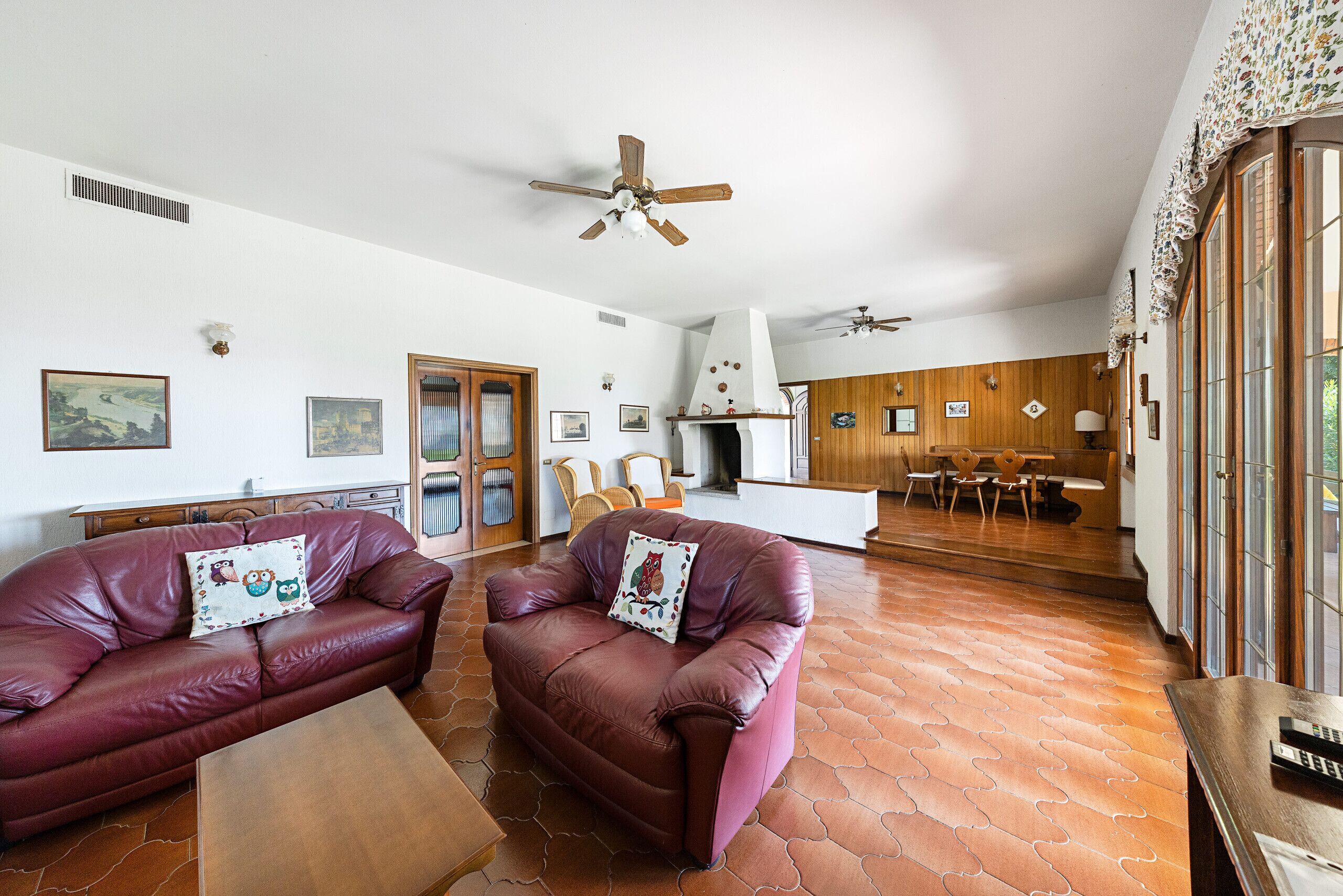 A spacious living room with leather sofas, a wooden coffee table, and a fireplace.