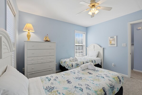 A bedroom with two beds, a dresser, a ceiling fan, and a window with blinds. - Oceanview Emerald Isle Retreat Near the Beach (Emerald Isle)