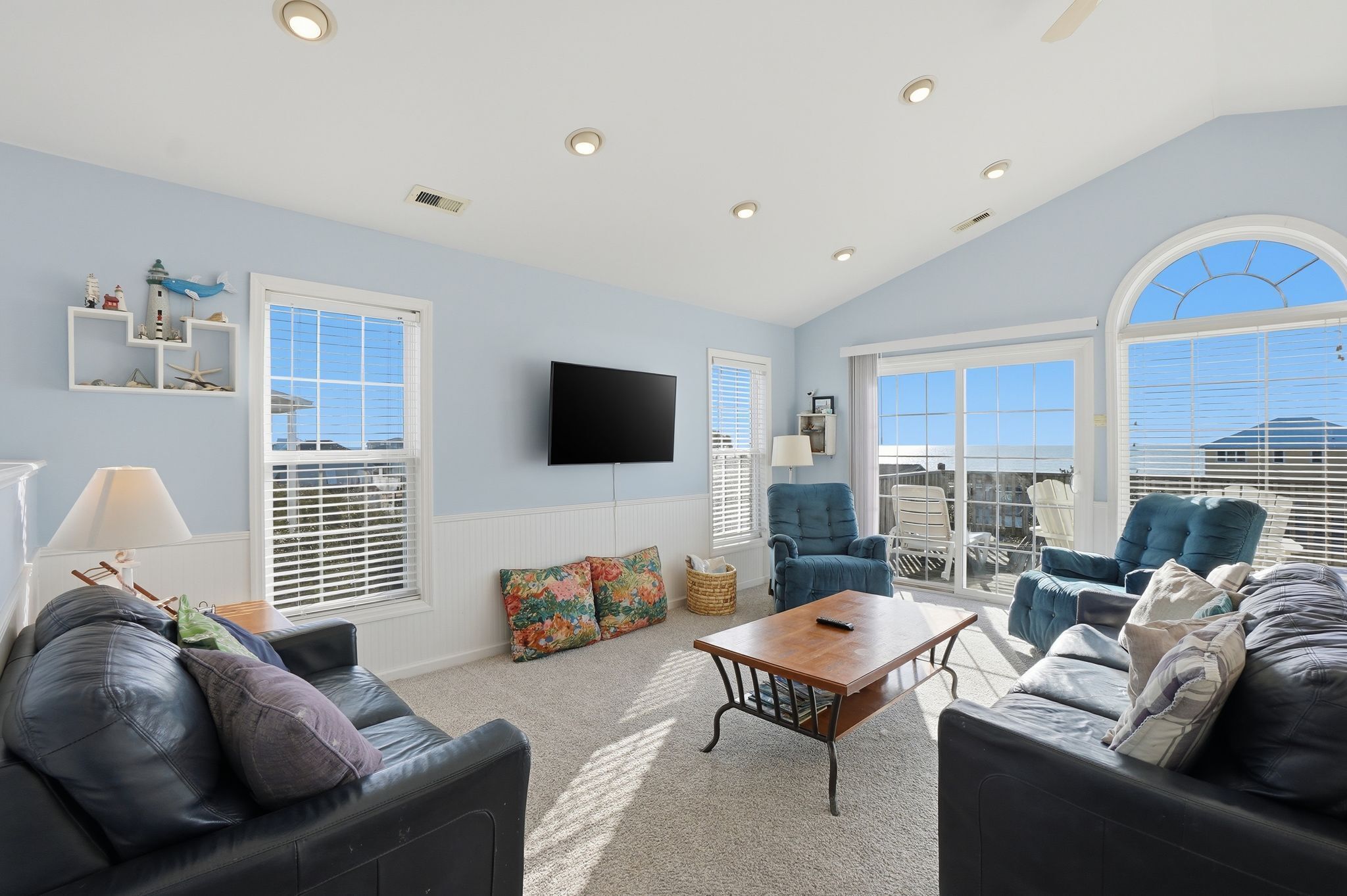 A spacious living room with a large window, a flat-screen TV, and a comfortable seating area.