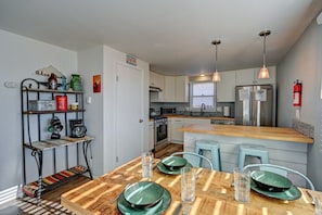 A modern kitchen with a wooden dining table, green plates, and a built-in island.