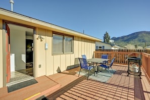 A covered outdoor area with a table and chairs, a barbecue grill, and a view of a mountain.