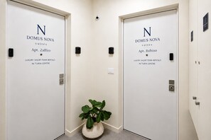 Two doors labeled 'DOMUS NOVA suites Apt. Zaffiro' and 'DOMUS NOVA suites Apt. Rubino' with a potted plant between them. - DomusNova Rubino | Suite historic center Turin (Torino)