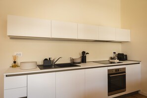 Eine moderne Küche mit weißen Schränken, einer schwarzen Arbeitsplatte, einem eingebauten Backofen und einer Edelstahl-Dunstabzugshaube.