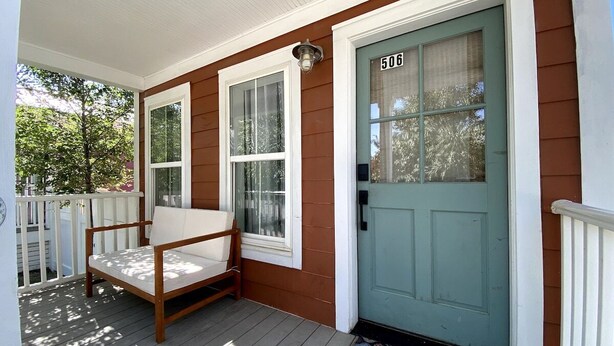 A porch with a wooden bench, a teal door with the number 506, and a welcome mat. - Off Main Downtown BV Cottage - STR-048 (Buena Vista)