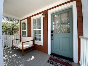 A porch with a wooden bench, a teal door with the number 506, and a welcome mat. - Off Main Downtown BV Cottage - STR-048 (Buena Vista)