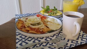 Una comida con nachos, ensalada y un refresco sobre un mantel estampado.