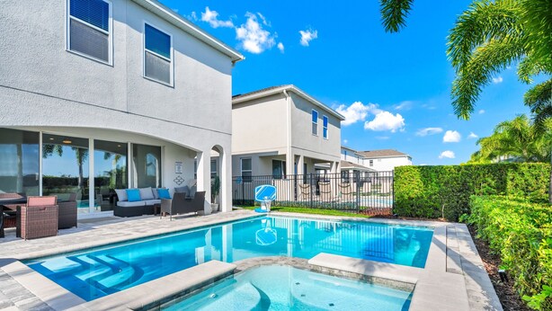 Ein Wohnhaus mit Swimmingpool, Gartenmöbeln und einer überdachten Terrasse.