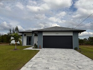 Une maison moderne à deux étages avec un garage, située au numéro 3401, qui se distingue par son allée pavée en motif à chevrons et sa pelouse bien entretenue.