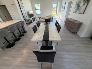 Une cuisine moderne avec une longue table à manger, des tabourets de bar et un four encastré.