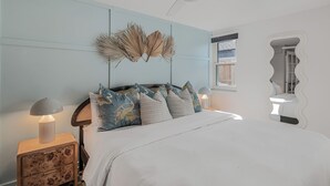 A bedroom with a bed, nightstands, a ceiling fan, and a wall-mounted mirror. - Art Deco Den - Charming 3 bedroom home with pool in Tampa (Tampa)