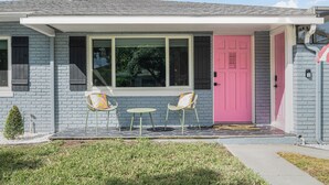 A house with a pink door, two chairs, and a small tree in the front yard. - Art Deco Den - Charming 3 bedroom home with pool in Tampa (Tampa)