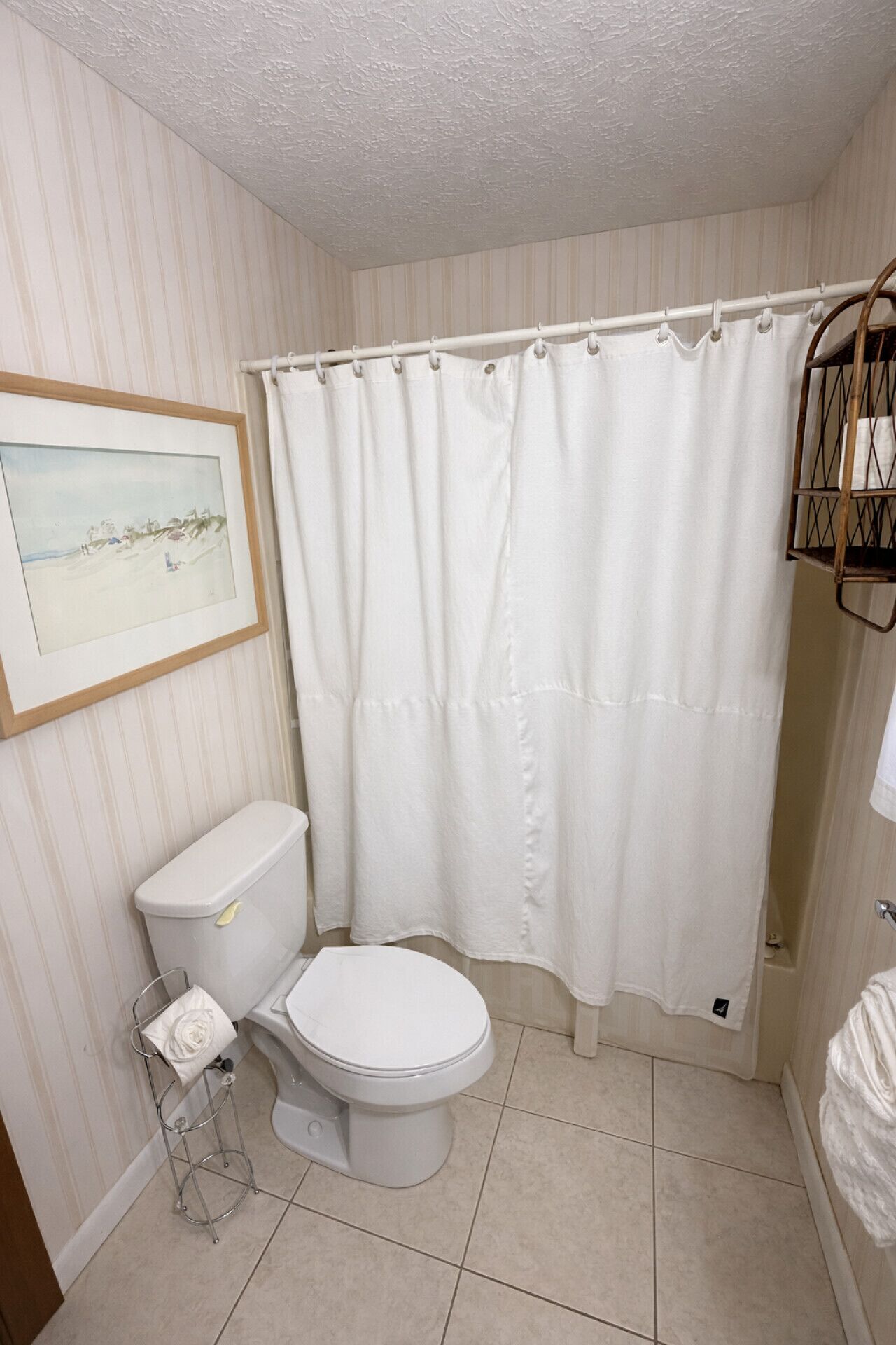 A bathroom with a toilet, a shower curtain, and a framed picture on the wall.