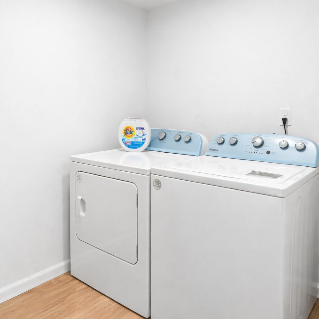 Een kleine wasruimte met een voorlader wasmachine en een droger met bovenlader.