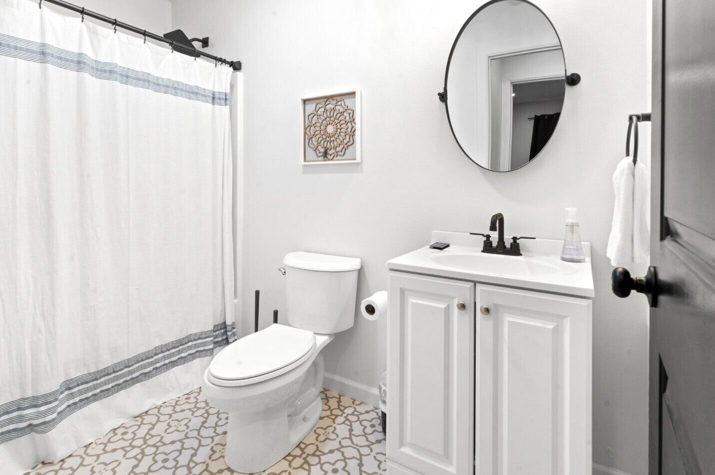 Une salle de bain équipée de toilettes, d’un lavabo, d’un miroir et d’un rideau de douche.