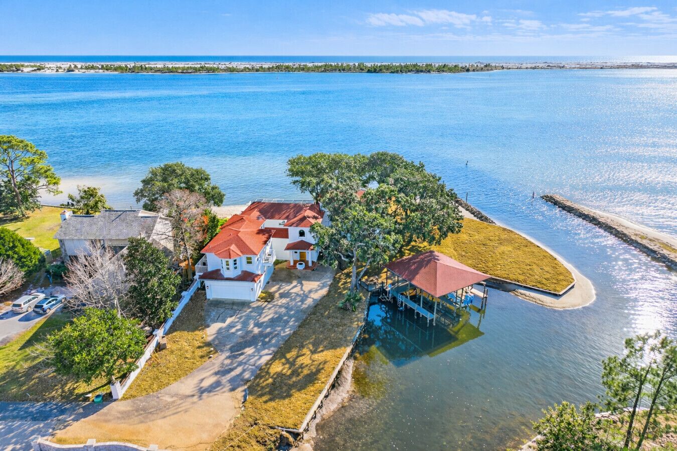 A waterfront property with multiple houses, a dock, and a clear view of the ocean.