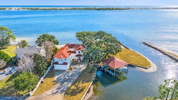 A waterfront property with multiple houses, a dock, and a clear view of the ocean.
