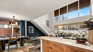 A spacious kitchen with a wooden countertop, a dining area with a table and chairs, a cozy seating area with a sofa and cushions, and a staircase leading to an upper level. - Eagle-Vail Family Retreat | Pool, Golf & Trails (Beaver Creek)