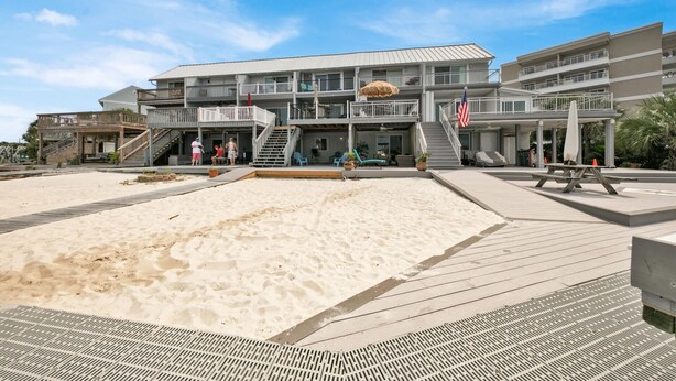 Et strandhotel med flere balkoner, et sandbad og en træpromenade.