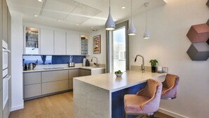 A modern kitchen with a central island, pendant lighting, and a view of the city. - Le 120m2 - luxury, swimming pool, terrace and garage (Nice)