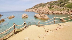 Une plage côtière avec une eau claire, des formations rocheuses et une clôture en bois.