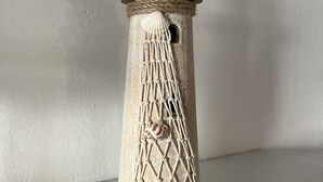 Un gros plan d’une colonne à la texture particulière, recouverte de cordelettes, avec un petit trou et un coquillage.