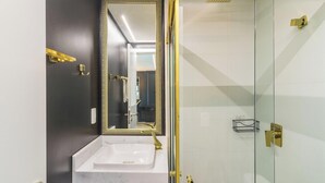 Een moderne badkamer met een witte wastafel, een grote spiegel en een douchecabine met glazen wanden.