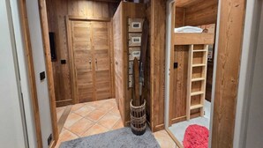 A wooden hallway with a tiled floor, a basket, and a red rug. - Le Menhir, Chalets de Lady (Megève)